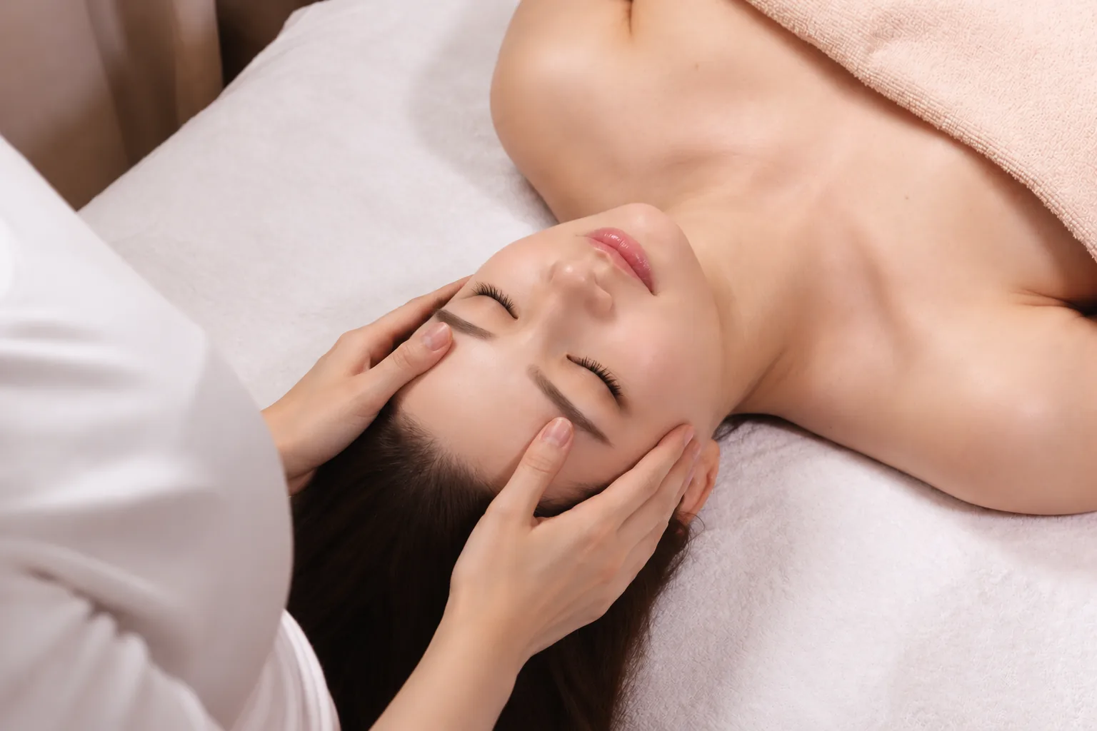 Woman receiving a relaxing facial treatment at YouniQue Aesthetics